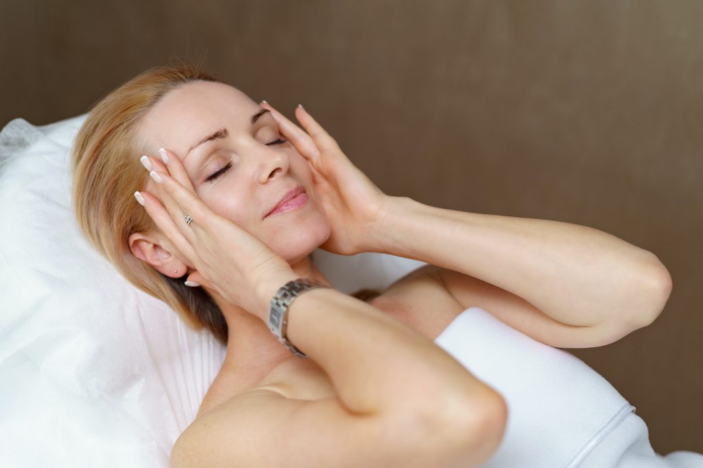 Satisfied smiling attractive woman after having taken the treatment for her face