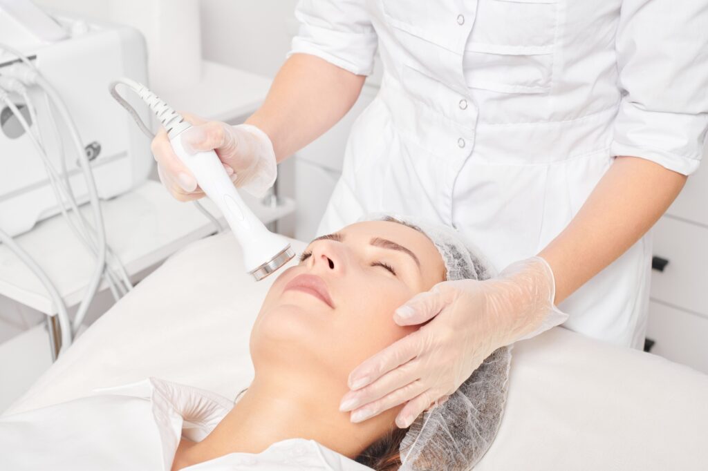 Cosmetologist makes ultrasound skin tightening for rejuvenation woman face using phonophoresis